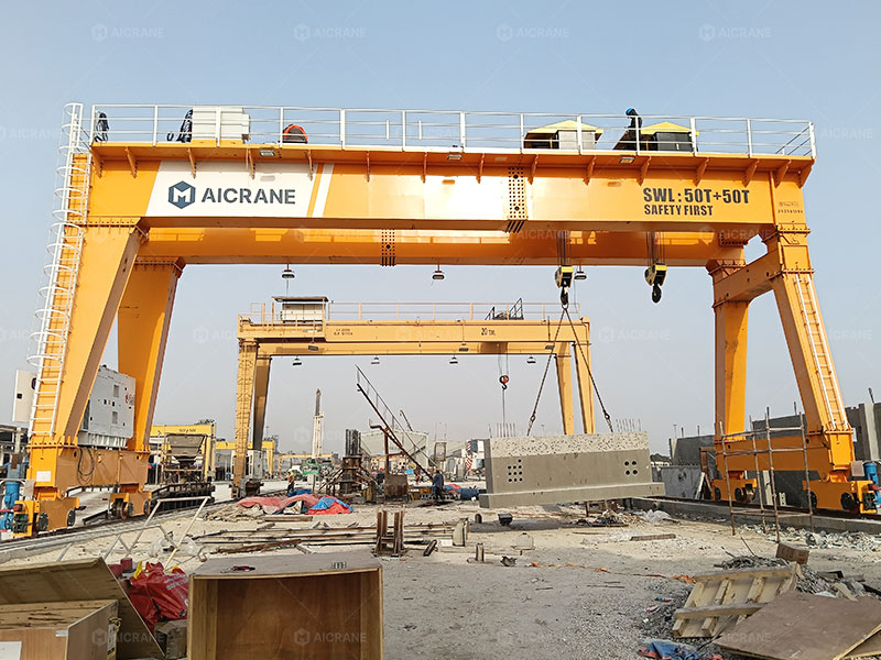 100 ton gantry crane lifting a precast concrete beam in an outdoor yard